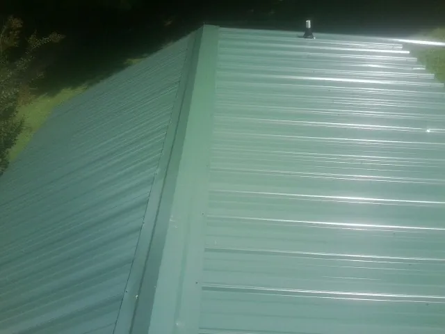 New green metal panels meeting at the ridge of a roof — Flat Roof Repair work by our crew in Bellingham